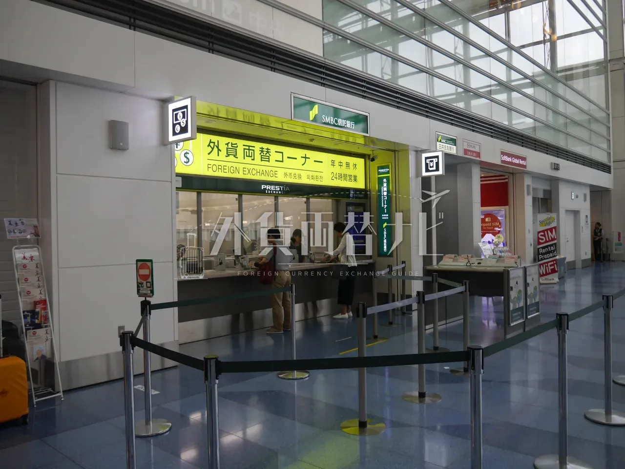 羽田空港 SMBC 信託銀行 PRESTIA の外貨両替コーナーで両替手続き中の利用客たち