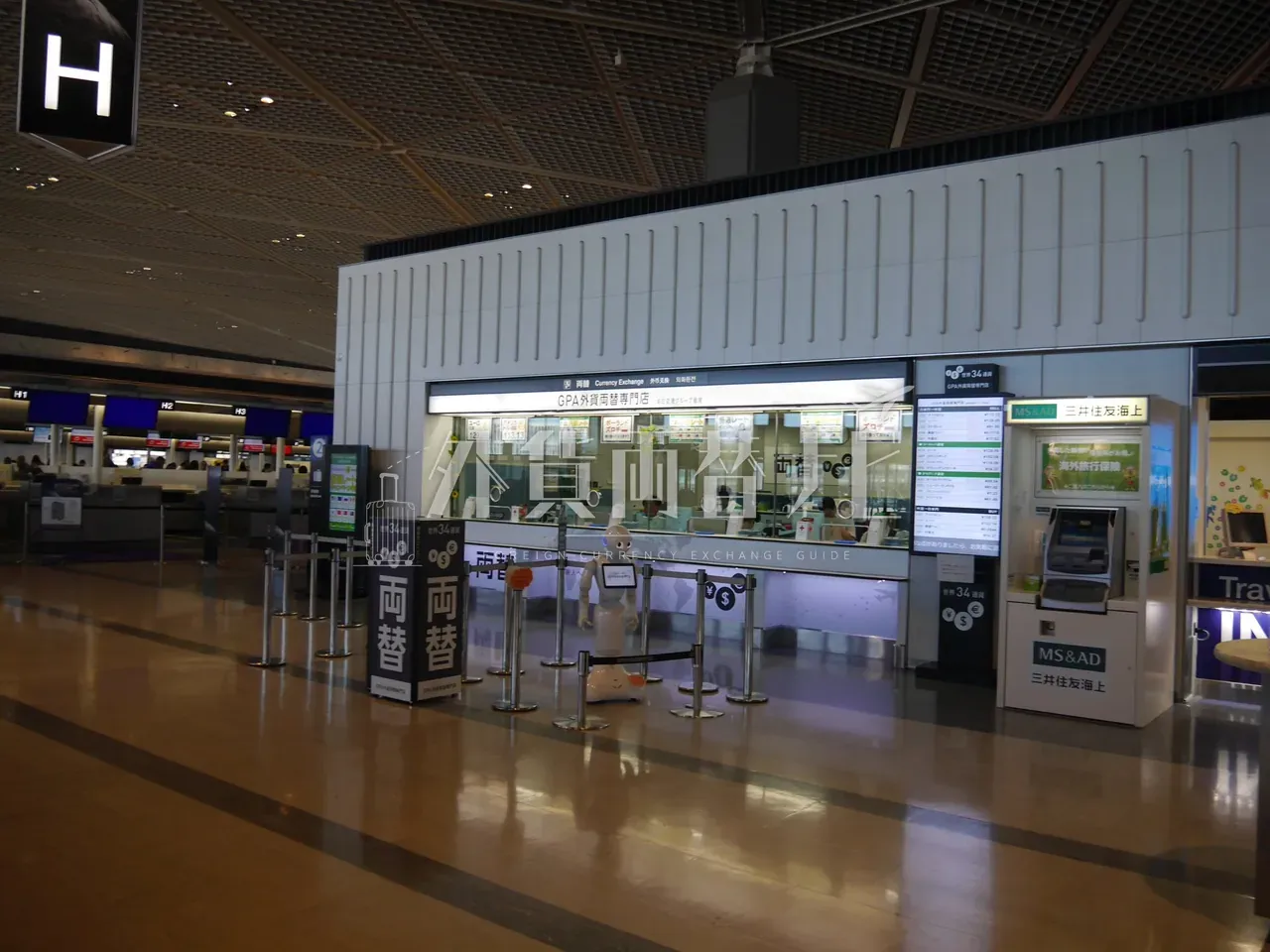 成田空港 GPA 外貨両替専門店のカウンター全景と接客中の Pepper ロボット、世界 34 通貨の縦長サイネージ