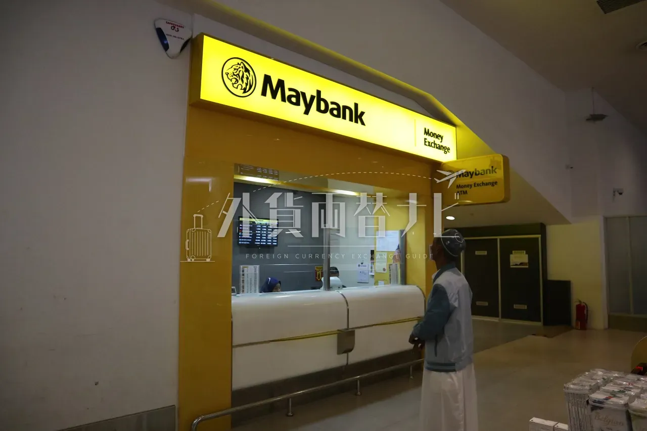 KLIA 空港の Maybank Money Exchange カウンターでスタッフと客が応対している様子