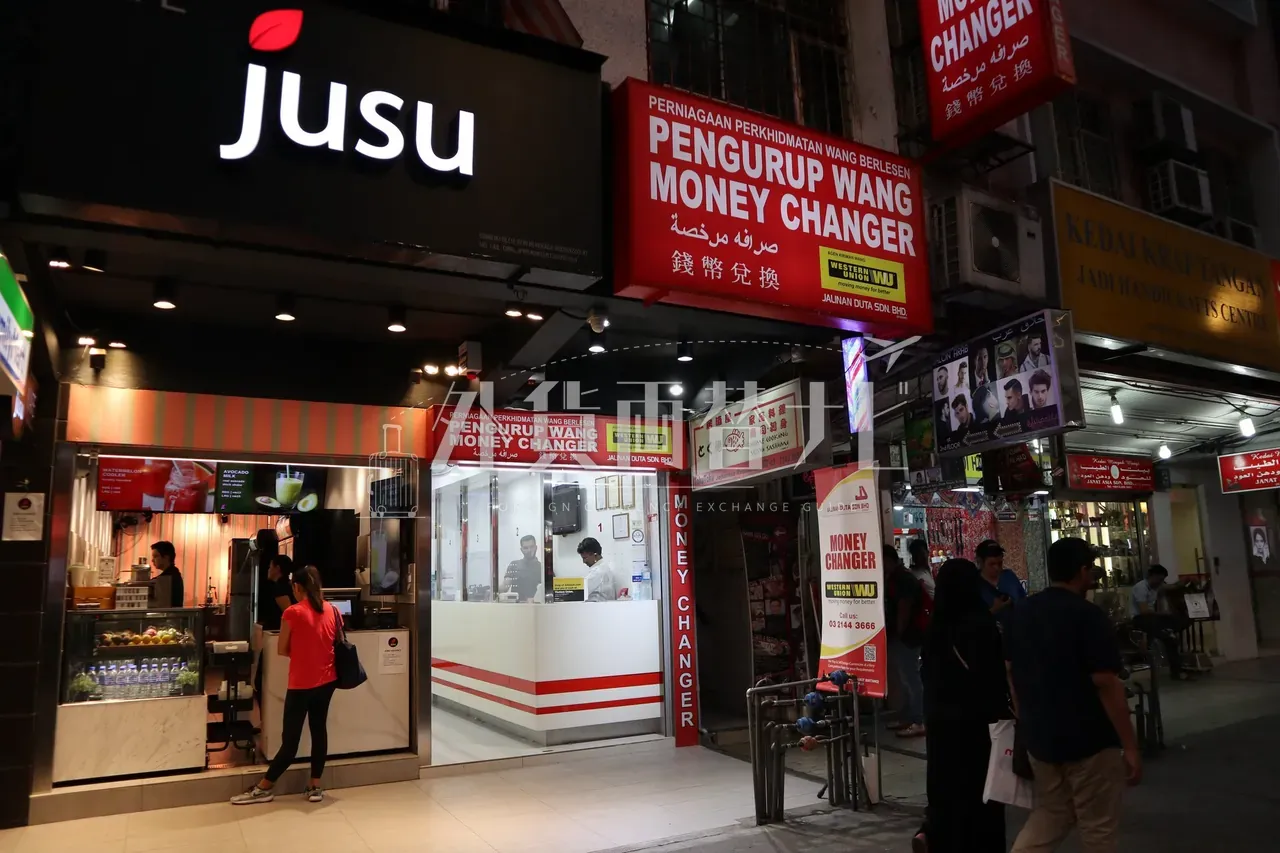 クアラルンプール・ブキッビンタンで夜に営業する両替所 JALINAN DUTA の店頭。多言語の看板が並ぶ