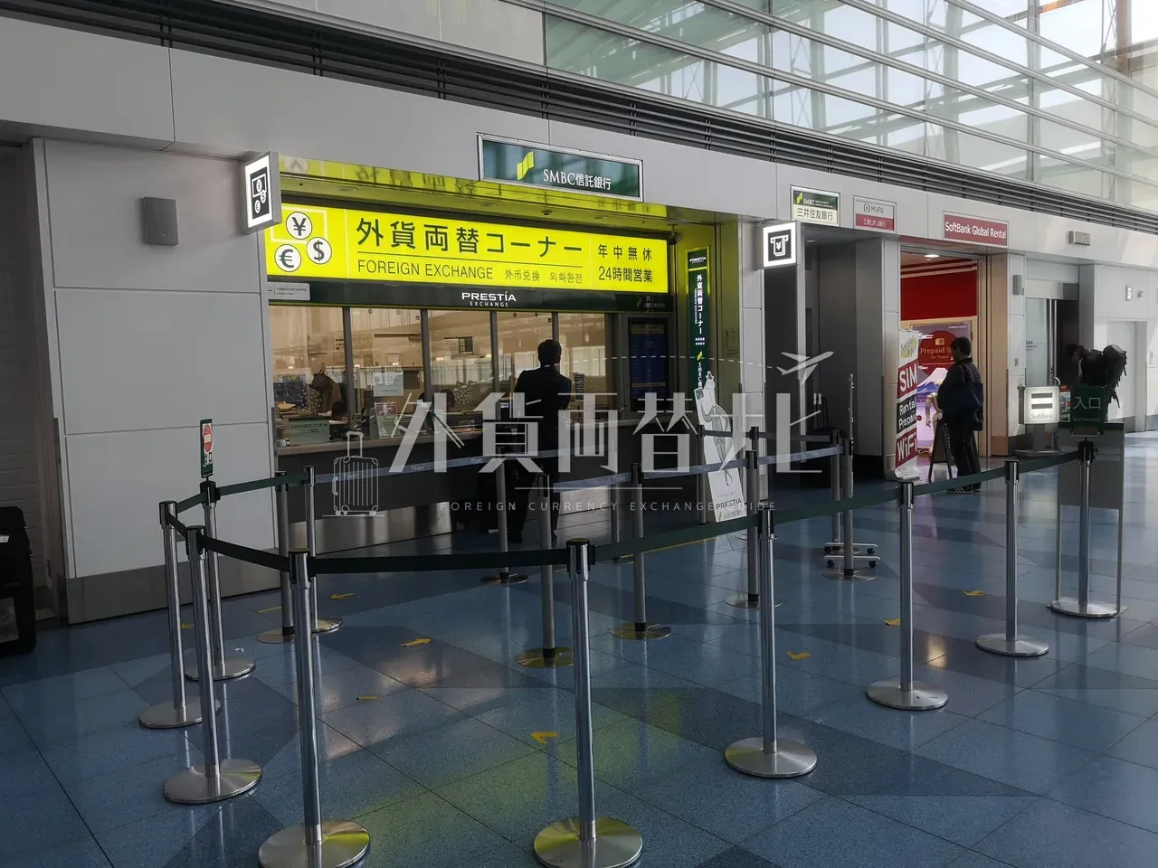 羽田空港 SMBC 信託銀行 PRESTIA の外貨両替コーナー。24 時間営業の窓口と整列スタンション