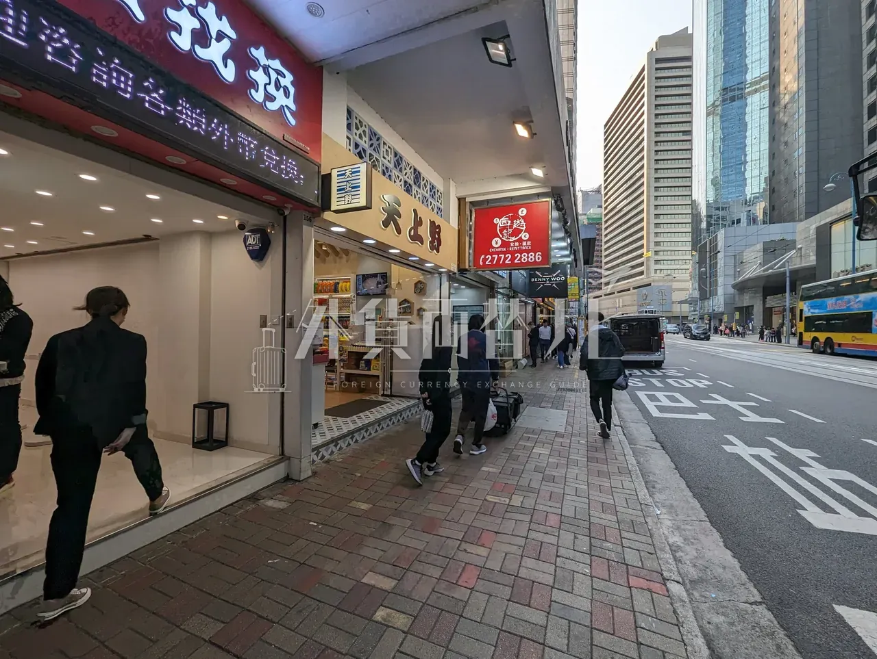 香港の街角に連なる外貨両替を扱う店舗群と歩道を歩く通行人