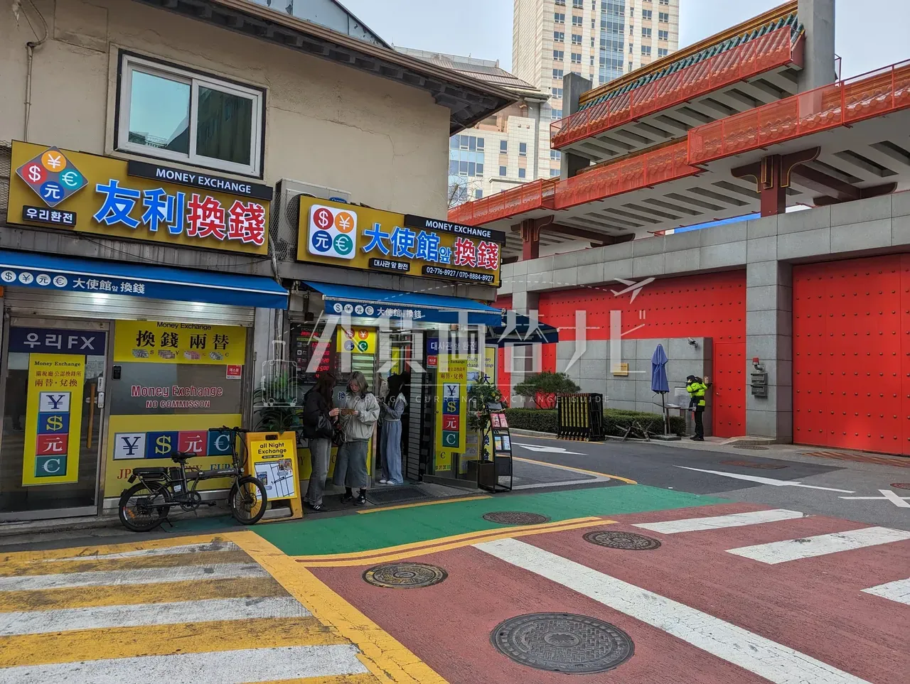 明洞の路地角に並ぶ「友利換銭」「大使館換銭」2軒の店頭で両替手続き中の客